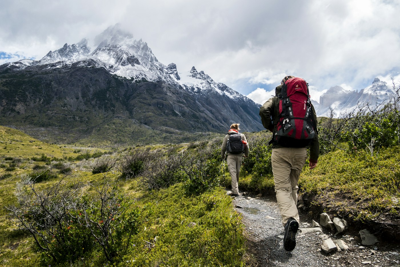 Two backpackers walking along a mountain trail.